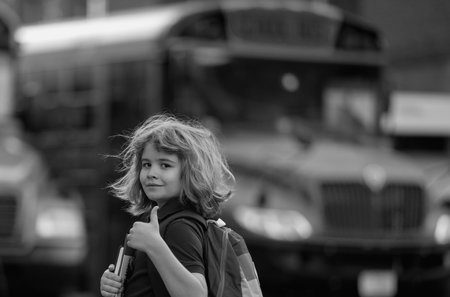 Schoolkid getting on the school bus. American School. Back to school. Kid of primary school. Happy...
