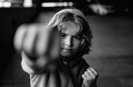 Aggressive child fight. Little kid boy fighting outside. Angry little boy showing fist. Portrait of fight kid. Bullied, physical abuse, children fighting. Aggression little boy. Kids bad behavioral.の写真素材