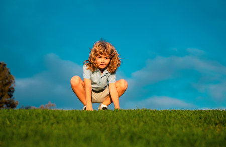 Funny redhead boy playing on the green grass in park, happy childhood. Kids active lifestyle...