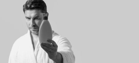 Banner of man with bottle of cosmetic products. Beauty man hold cosmetic bottle. Cosmetics cream for skincare. Spa beauty products. Man advertising bottle with dispenser for liquid soap, gel or foam.の写真素材