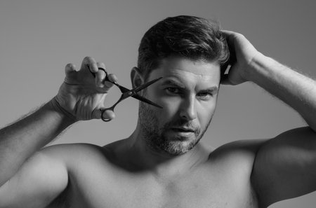 Caucasian man trying to make a hair cut by himself with scissors. Male haircut. Barber scissors,...
