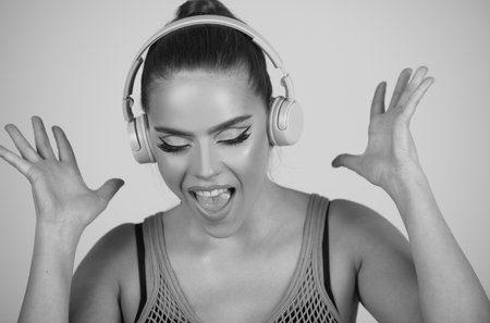 Close up portrait of amazed dancing girl listening to music with headphones isolated over studio background. Excited young girl with headphones.の写真素材