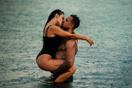 Romantic lovers kiss in water. Tender lovers kissing outdoor. Summer kiss. Couple kissed in rain. Sensual couple kissing under a rain in water. Summer couple kissing at date.の写真素材