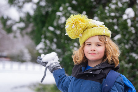 Kids play with snow in winter park. First Winter snow. Kids winters holiday. Happy kid boy playing with snow in winter park. Portrait kid throw snowballs. Funny snow. Winter kids in snowball outdoor.の写真素材