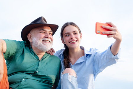 Selfie with parents. Grandchild girl teaching grandad take selfies. Daughter and old father using...