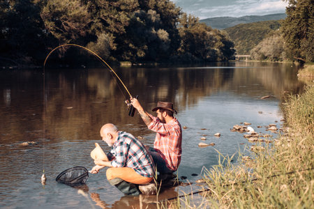 Father and mature son fisherman fishing with a fishing rod on river.の写真素材