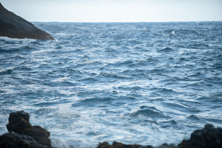 Cooled black lava beaten by the Atlantic ocean waves. View of sea waves hitting rocks on the beach. Waves and rocks.の写真素材