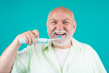 Brushing teeth. Senior holding toothbrush for tooth brushing. Dentistry, white tooth. Healthy teeth and dental care. Whitening toothpaste and brush for mature. Cleaning teeth. Oral hygiene.の写真素材