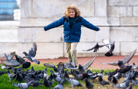 Happy child chasing birds on autumn day. Child run for pigeons. Carefree kids concept. Happy childhood. A Happy child chases pigeons in park. Happy Child playing with doves. Carefree Kid run pigeons.の写真素材