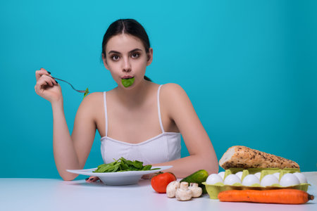 Vegetables diet. Young woman eating healthy food, dieting. Girl eating vegetable diet salad in studio. Vegan salad. Female on diet. Dieting concept. Healthy lifestyle. Diet for weight loss.の写真素材