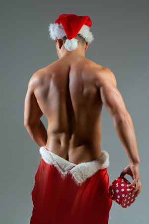 Sexy Santa. Back of men in Santa hat. New year strip and gifts for adults. Muscle man at xmas. Santa with muscular body. Christmas party. Handsome sexy santa for club banner.の写真素材