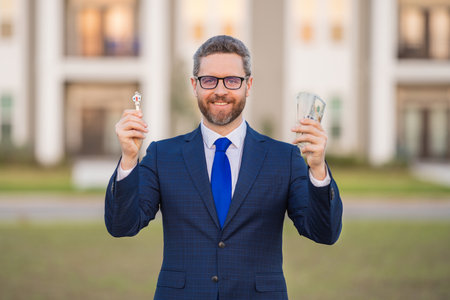 Loan. Real estate agent hold money dollars and keys from new home with loan. Real estate agent offers loan. Man broker or real estate agent ready to loan. Good loans.の写真素材