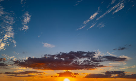 Sunset background. Dramatic majestic scenery sunset. Sky with clouds in sunset sky light background. Sunrise with clouds in various shapes. Calm sunset sky and sun through clouds over.の写真素材