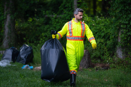 Volunteer helps to pick up garbage. Pollute forest. Rubbish trash. Planet pollution environmental protection concept. Cleaning up the forest. Putting trash in garbage bags, environmental protection.の写真素材