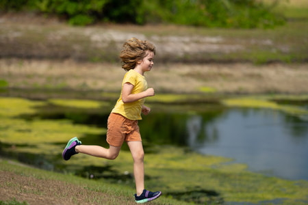 Sporty young child running jogging and training outdoor. Run and healthy sport for children. Child running on street kids fitness. Running training outdoor, morning jogging. Run exercising.の写真素材
