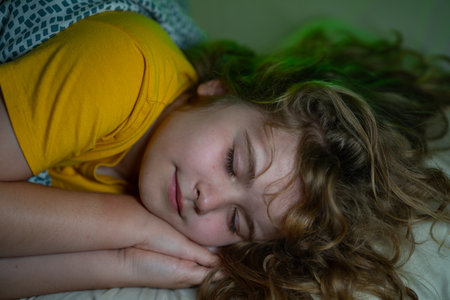 Child sleeping in a bed. Cute kid sleep. Kids pillow and blanket for sleeping. Kid sleeping in dark bedroom. Child sleeping on a bed at home.の写真素材