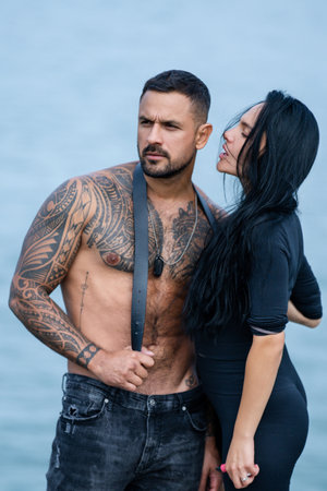 Loving people, lovely couple in love. Sexy girl and fit muscular boyfriend with naked bare torso kissing outdoor. Tattooed Hispanic man posing with sexy woman outdoor.の写真素材