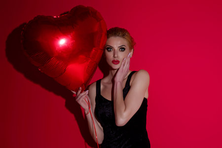 Valentines day, love heart. Portrait of lovely valentine girl hold red heart. Beautiful woman celebrate valentines day. Woman in love. Woman on valentines party. Symbol of love. Valentine card.の写真素材