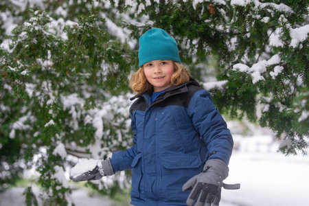 Kids play with snow in winter park. First Winter snow. Kids winters holiday. Happy kid boy playing with snow in winter park. Portrait kid throw snowballs. Funny snow. Winter kids in snowball outdoor.の写真素材