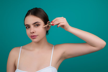 Dropping serum collagen moisturizer. Beauty woman dripping moisturizing serum from pipette on face during beauty procedure in studio. Serum Protector skin. Facial Treatment serum oil. Beauty and spa.の写真素材
