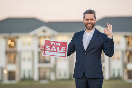 House owner, real estate agents hold sign for sale. Housing estates in the project, buying and selling housing estates. Real estate trading ideas and bank loans for buying and selling houses and land.の写真素材