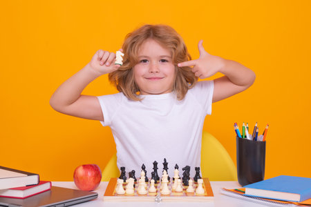 Kid thinking about chess. The concept of learning and growing children. Little chess player on yellow isolated studio background.の写真素材
