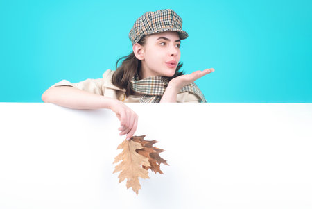 Studio isolated portrait of young happy woman with autumn fall leaves. Attractive caucasian smiling woman with yellow maple leaf. Autumn portrait of attractive woman wearing french beret ans scarf.の写真素材