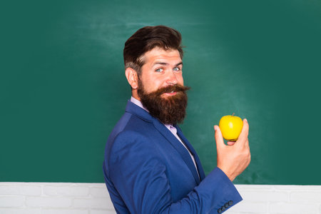 Portrait of a funny teacher or professor near blackboard. Thinking serious mature teacher. Mature professor, middle aged teacher, bearded man.の写真素材