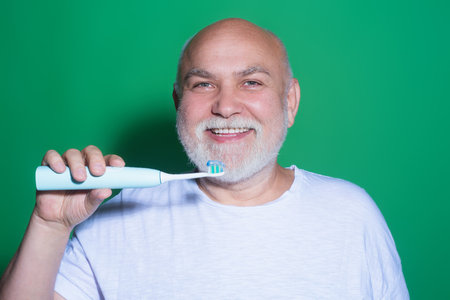 Brushing teeth. Senior holding toothbrush for tooth brushing. Dentistry, white tooth. Healthy teeth and dental care. Whitening toothpaste and brush for mature old man. Cleaning teeth. Oral hygiene.の写真素材