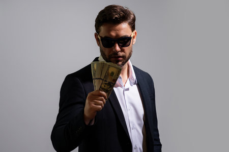 Business man in t-shirt with cash money dollars banknotes isolated on studio background. Hundred dollar bill, financial concept.の写真素材