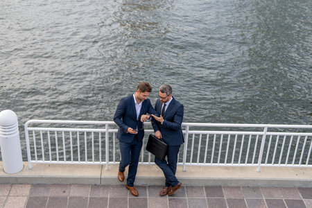 Business partners talking outdoor. Photo of business partners talk conversation outdoor. Two handsome businessmen in suits discuss a working project against the background of urban city.の写真素材