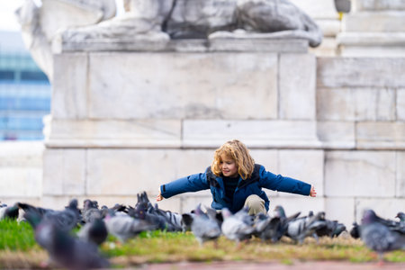 Carefree child chasing birds on autumn day. Child run for pigeons. Carefree kids concept. Happy childhood. A child chases pigeons in park. Carefree Child playing with doves. Carefree Kid run pigeons.の写真素材