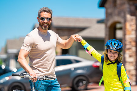 Father and daughter learning to ride a bicycle having fun together at Fathers day. Father teaching his daughter cycling on bike in american neighborhood. Father and daughter concept. Father support daughter.の写真素材