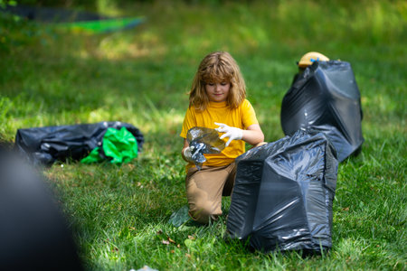 Kid in rubber gloves with trash bag clean up garbage on forest outdoor. Eco, environment conservation. Recycle pollution. Kid boy collecting garbage and plastic trash. Save environment. Eco kids.の写真素材