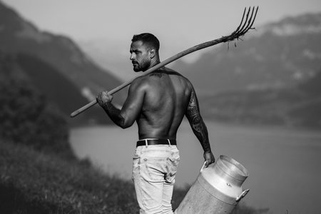 Sexy Man farmer on countryside farm. Farmer with bare naked torso. Muscular sexy farm worker in the farm field. Strong shirtless Farmer on rural farm. Male farmer at his land.の写真素材