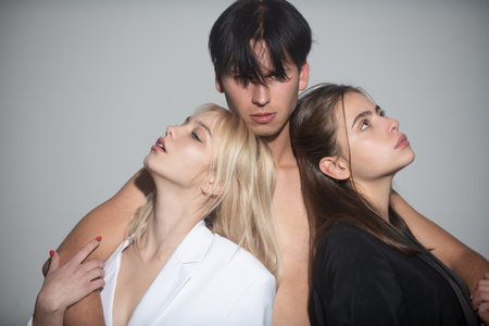 Polyamory and polygamy. Threesome of man and two sexy woman. Romantic relationships of Threesome. A group of sexy models. Fashion people. Love and romance. Polygamy, swingers. Friends sexy.の写真素材