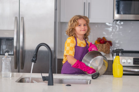 Child doing housework. Cute child helping with household, wiping dishes in kitchen. Adorable little helper child housekeeping. Little cute child cleaning dishes at kitchen.の写真素材