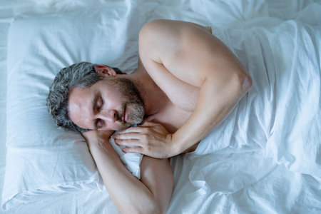 Man sleeps in bed. Sleep and nap. Snore sleepy napping wake up. Mattress pillow bed. Slumber overslept. Morning sleep. Hispanic man sleeping in bedroom. Close up bearded man in cozy comfort bed.の写真素材
