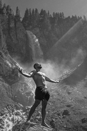 Man tourist on summer vacation. Handsome man with naked torso on summer vacation day. Sexy hiker outside. Tourist man walking on the waterfall landscape. Man Traveling and nature. Black white photo.の写真素材