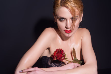 Portrait of attractive lovely charming dreamy girl holding red roses, isolated on black studio background.の写真素材