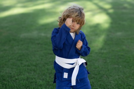 Little karate fighter. Kid boy practicing sport outdoor. Sport karate kids fighter. Little boy wearing kimono doing karate fight in park. Child sport fighting. Little karate fighter. Child sport.の写真素材