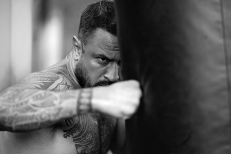 Serious danger man boxing punching bag. Man boxer face close up. Knockout. Fists fight. Sport Man ready for boxings challenge. Mans fight. Boxings fight. Boxing sport.の写真素材