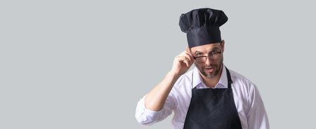 Handsome bearded male chef cook or baker man in uniform shirt posing isolated on yellow background,...