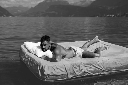 Summer Travel vacation holiday. Man rest at the lake, enjoy summer holiday. Muscular man lying on...