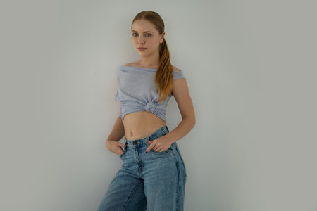 Young woman in jeans. Blonde woman wear classic outfit isolated on gray background. Model in trendy...