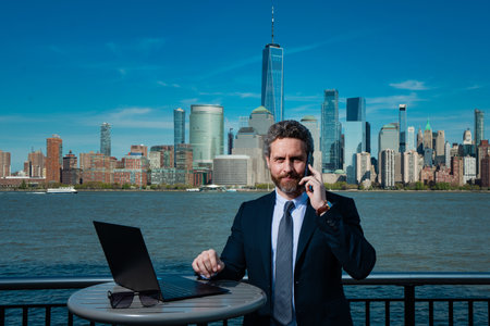 Business man using laptop outdoor in New York City. Business American success. American business dream. American businessmen in suits with laptop near Manhattan. Online business in USA.の写真素材