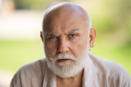 Middle-aged senior grandfather close up portrait. Grey hair white beard old man. Senior serious. Face of bearded senior age man. Closeup emotional portrait of an old mature senior man with grey beard.の写真素材