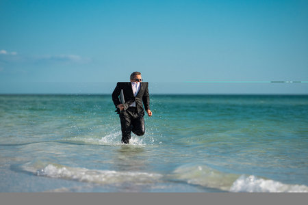 Excited millennial hispanic business man in suit on sea. Summer vacation, business on sea beach. 40s business man on summer business travel. Dream for summer vacations office workers.の写真素材