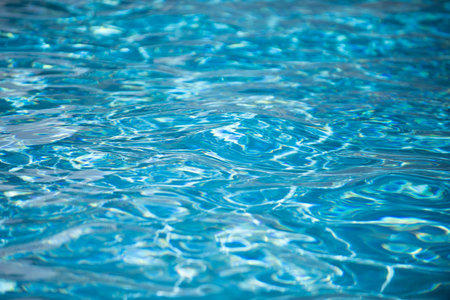 Water background. Blue water, ripples and highlights. Texture of water surface and tiled bottom.