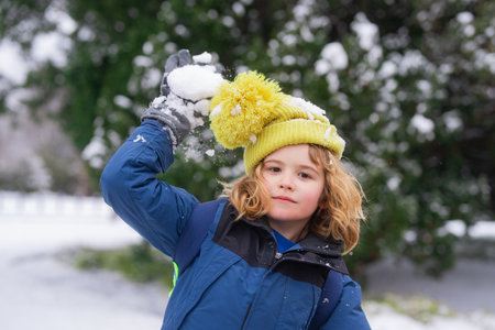 Kid with snowball in snow. Winter holiday kids, snowball snowball activity. Child enjoy Christmas vacation. Kid in winter clothes in snowy forest. Trees covered white snow. Kid have fun playing snow snowball.の写真素材